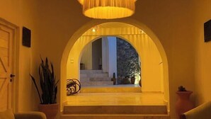 An interior with a large, circular, multi-tiered chandelier hanging from the ceiling, an arched doorway leading to an outdoor area, and two sofas positioned on either side of the doorway. - ALTAMONTE HOTEL BOUTIQUE (Ezequiel Montes)