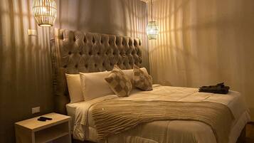 A neatly made bed with a tufted headboard, two pillows, and a folded towel on the side.
