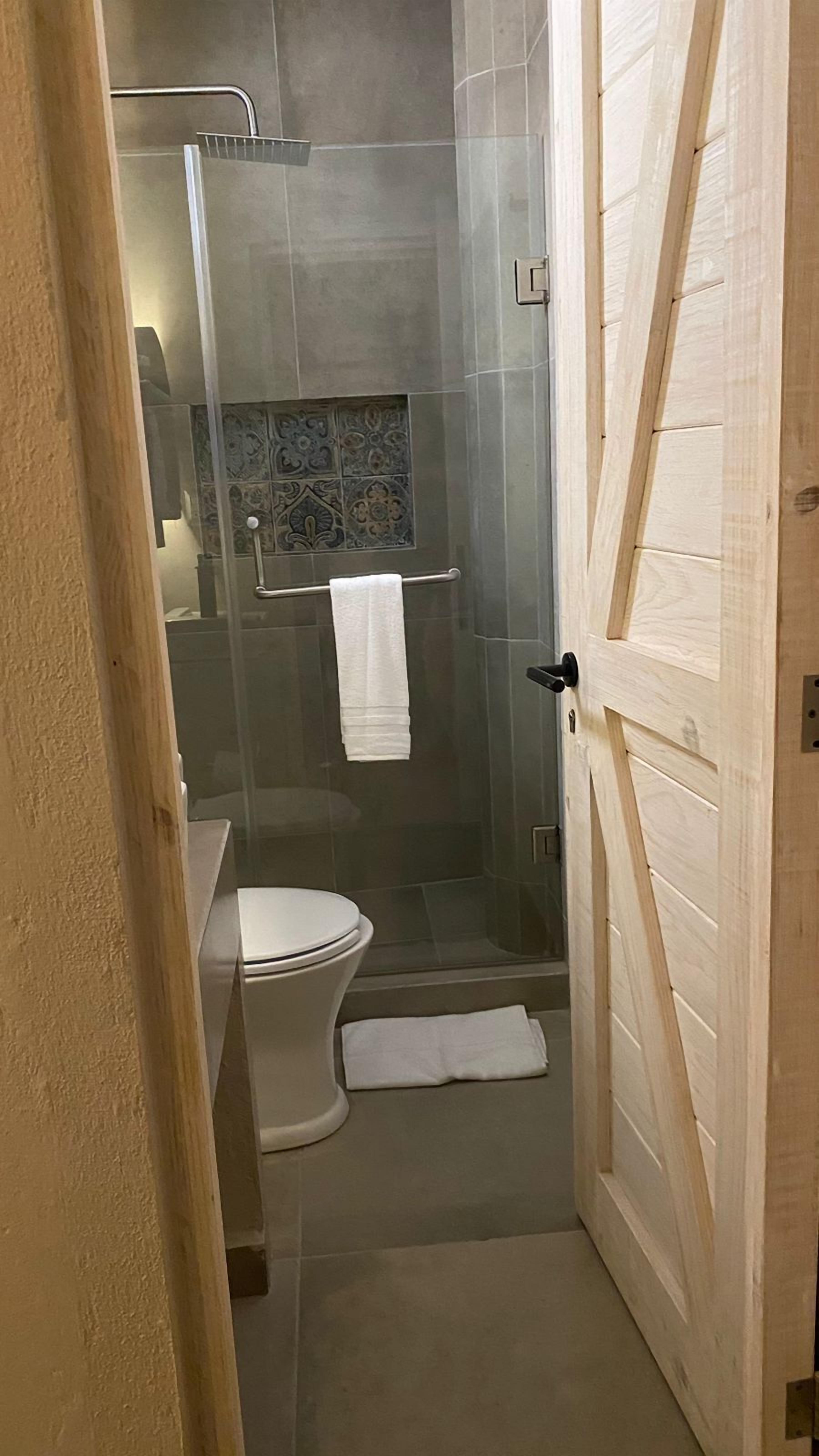 Un baño con inodoro, ducha y puerta de vidrio.