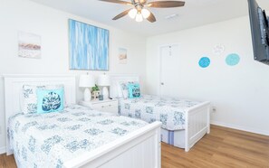 A bedroom with two beds, a ceiling fan, and artwork on the walls. - Steps to Beach | Private Balconies | Relax Here (Jacksonville Beach)