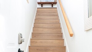 A wooden staircase with a handrail, white walls, and a welcome sign at the top. - Steps to Beach | Private Balconies | Relax Here (Jacksonville Beach)
