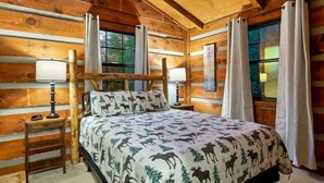 A log cabin bedroom with a bed, two bedside tables, and a window with curtains. - Tree House Tranquility Cabin Close to Dollywood (Sevierville)