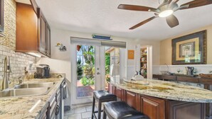 A kitchen with a large island, double sinks, and a ceiling fan.