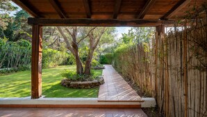 Un patio couvert, avec un chemin de pierre menant à un jardin verdoyant.