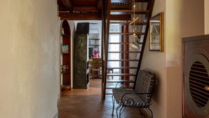 Un couloir avec un plafond en bois, une chaise et un radiateur.