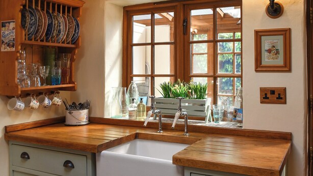 Una cocina con encimera de madera, un fregadero y un ventanal con vistas a la vegetación.