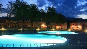 Ein Schwimmbeckenbereich bei Dämmerung, im Hintergrund sind Gebäude zu sehen.