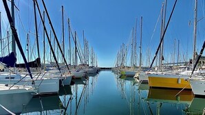 Ein Yachthafen mit mehreren Segelbooten, Holzstegen und ruhigem Wasser, das die Boote spiegelt.