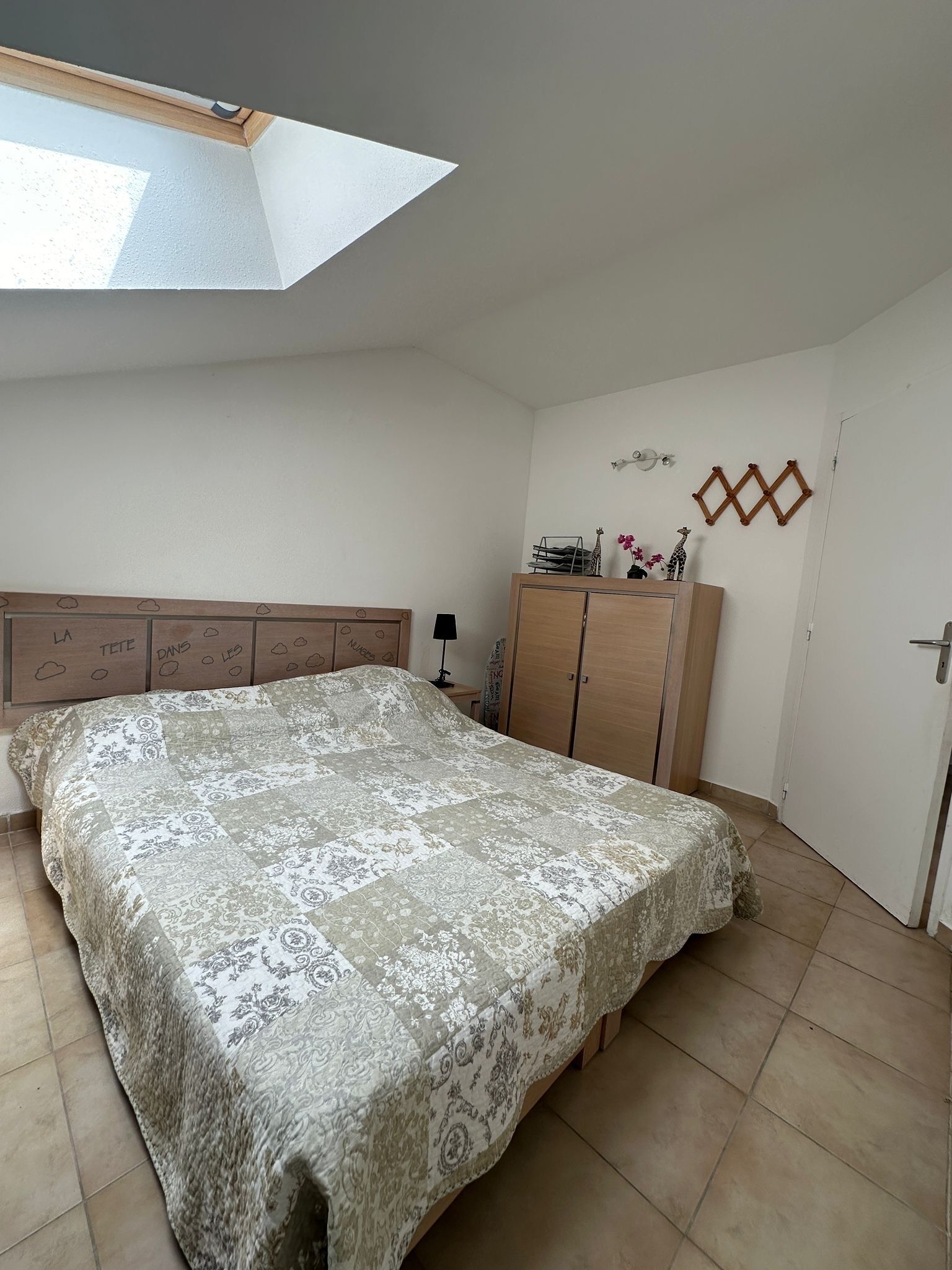 Un dormitorio con cama, armario, escritorio y estante en la pared.