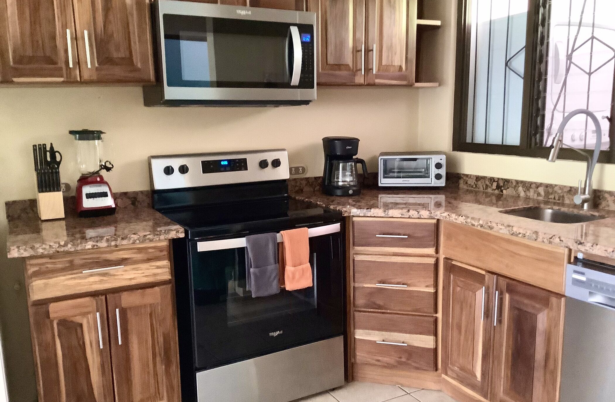 A kitchen with wooden cabinets, a stainless steel oven, a microwave, a coffee maker, and a toaster.