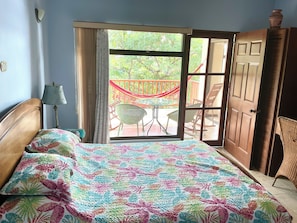 Une pièce avec un lit, une fenêtre, une porte, une chaise et une table à l’extérieur.