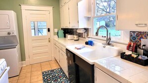 A compact kitchen with white cabinets, a built-in dishwasher, a sink, and a window providing a view of the outside. - Fully Fenced Yard, Dogs Welcome, Near MSU and Cox South (Springfield)