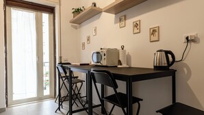 A small kitchen with a table, two chairs, a microwave, a kettle, and a window with a view. - Via Coriolano 8 - Three Bedroom Apartment, Sleeps 6 (Naples)