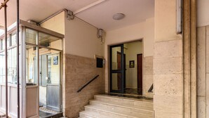 A building entrance with a glass door, a set of stairs, and a metal handrail. - Via Coriolano 8 - Three Bedroom Apartment, Sleeps 6 (Naples)