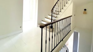Un interior espacioso con una gran escalera, una araña y una distribución luminosa y abierta.