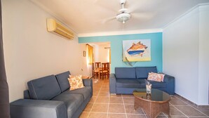 Un salon avec deux canapés, une table basse et un ventilateur de plafond.