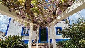 A white pergola with purple flowers, a blue and white building with a green door, and a gravel path. - 5 Bed Country Villa with Large Heated Pool near Óbidos (A dos Ruivos)