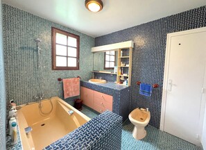 A bathroom with a bathtub, sink, toilet, and a window. - Family home in South Vendée, between land and sea, in a quiet, wooded garden. (Luçon)