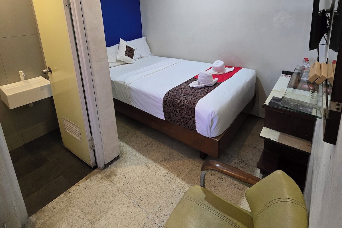 Ein Hotelzimmer mit Bett, Schreibtisch, Stuhl und Badezimmer.