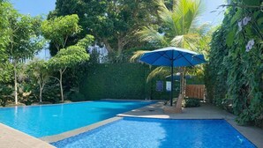 A swimming pool with a blue tiled edge, surrounded by lush greenery and a palm tree. - Kusma Hotel Bandungan Semarang (Bandungan)