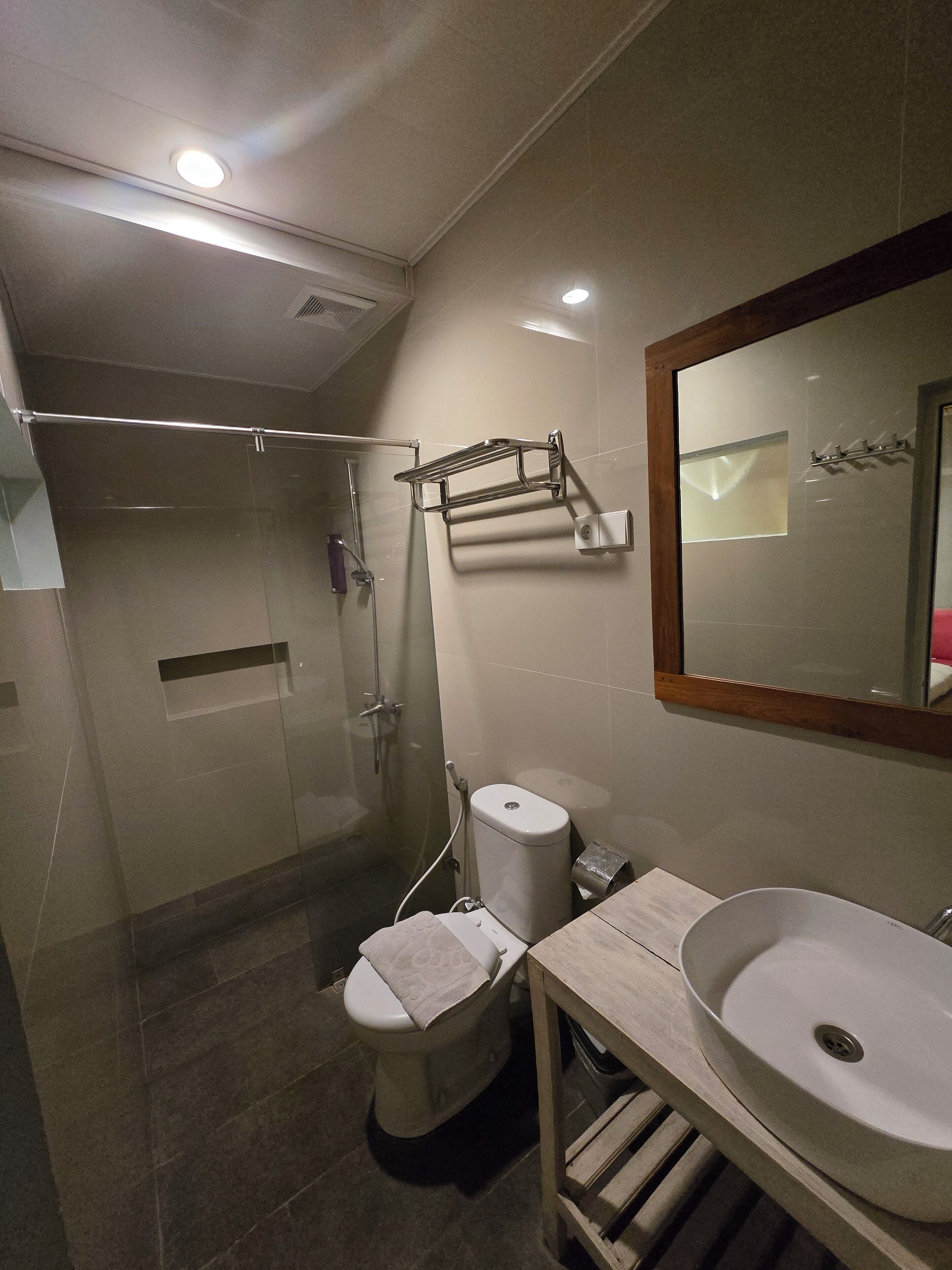 A modern bathroom with a glass-enclosed shower, a toilet, and a sink with a mirror above it.