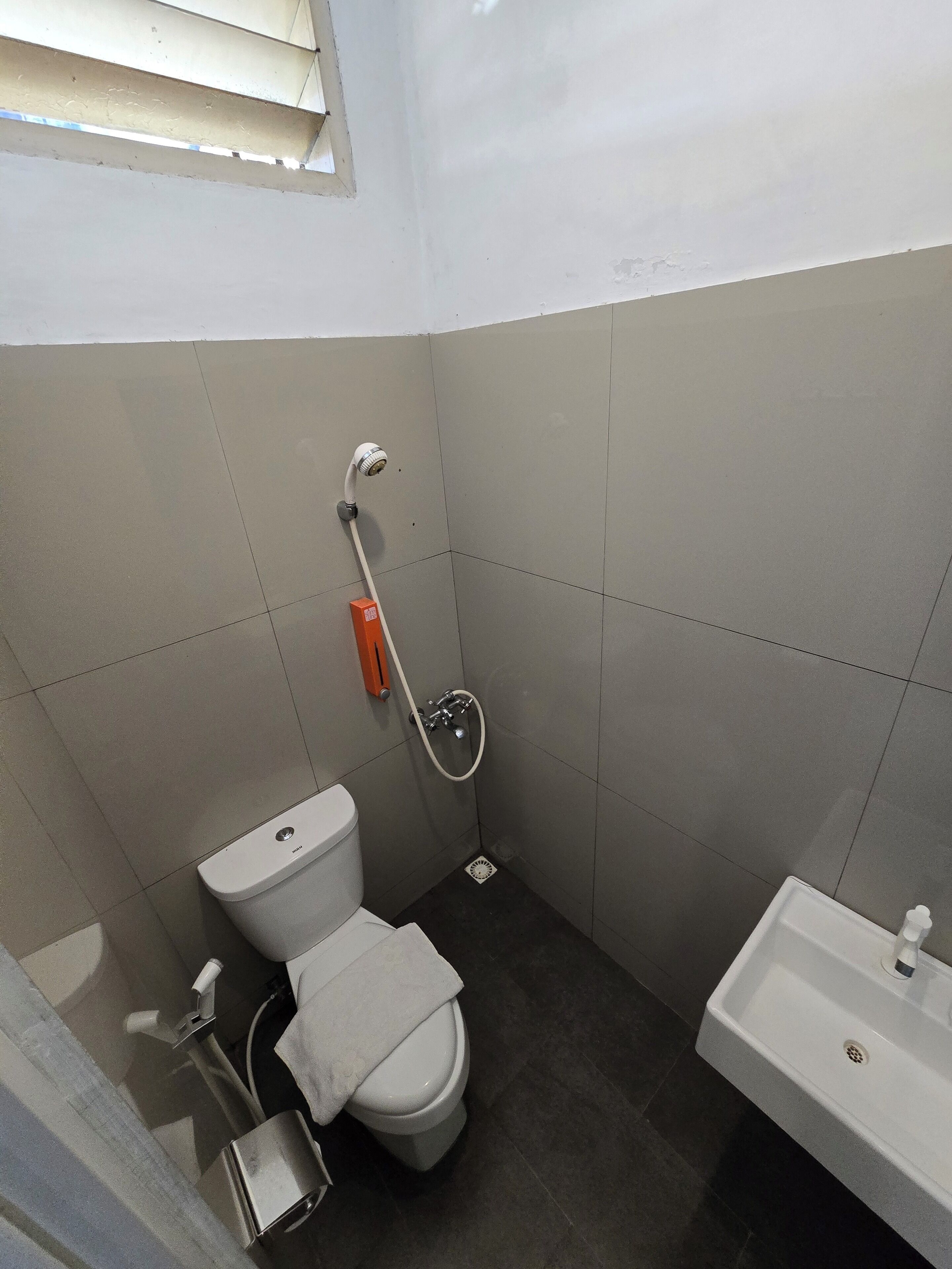 Un baño pequeño con inodoro, lavamanos y ducha.