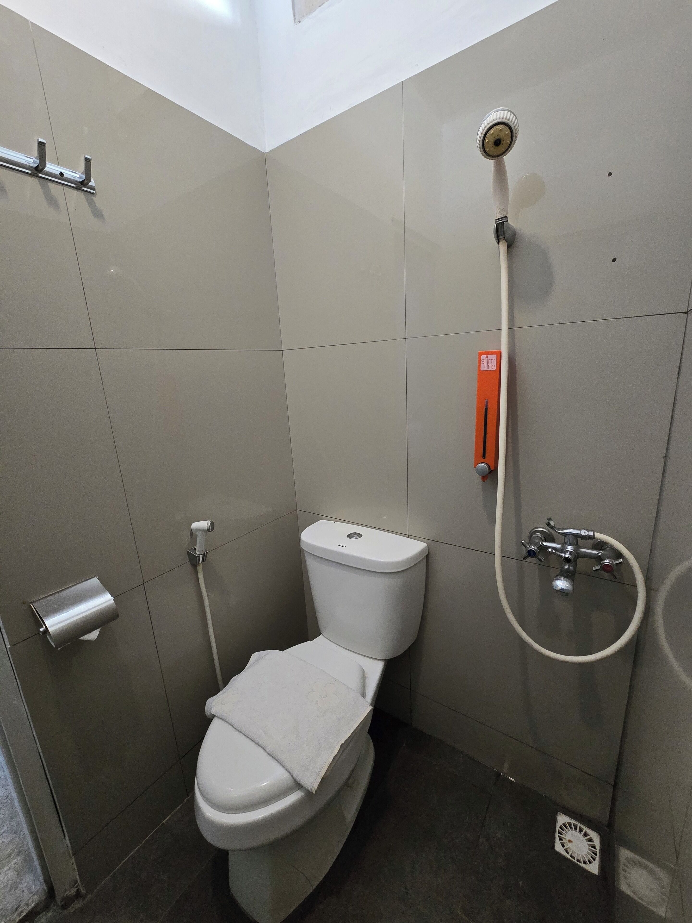 A small, modern bathroom with a toilet, a shower, and a hand dryer.