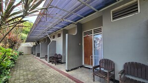 A covered walkway with hexagonal tiles, benches, and a door with an exit sign. - Kusma Hotel Bandungan Semarang (Bandungan)