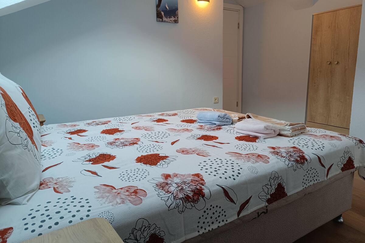 A bedroom with a bed, a wall-mounted light, a door, and a wardrobe.