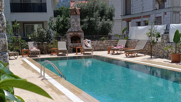 Piscina com espreguiçadeiras e lareira de pedra.