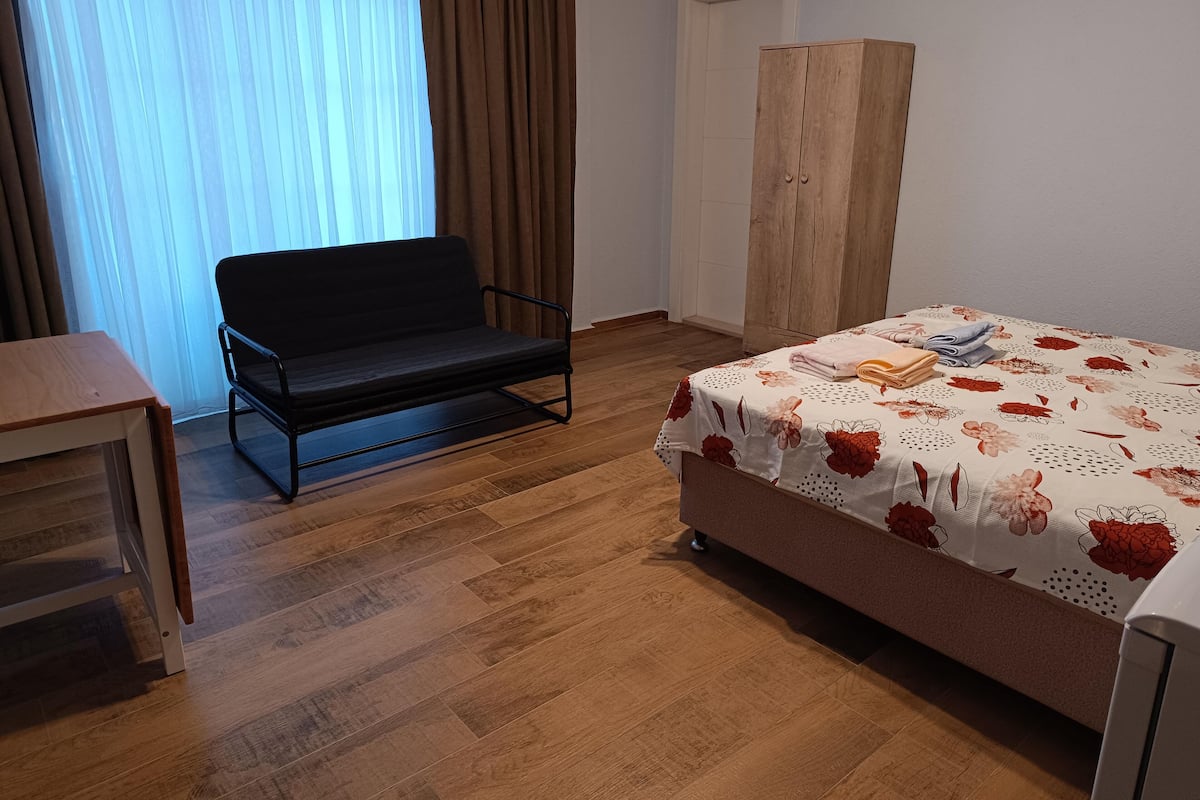 A room with a bed, a sofa, a wardrobe, and a table.