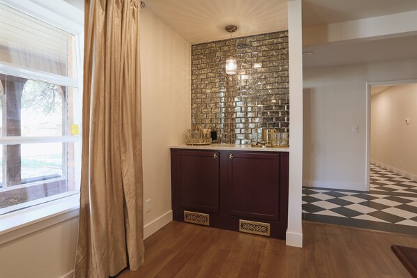 A kitchen with dark cabinets, a tiled backsplash, and a window with curtains.