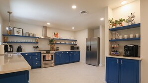 Una cocina moderna con armarios azules, electrodomésticos de acero inoxidable y encimeras blancas.