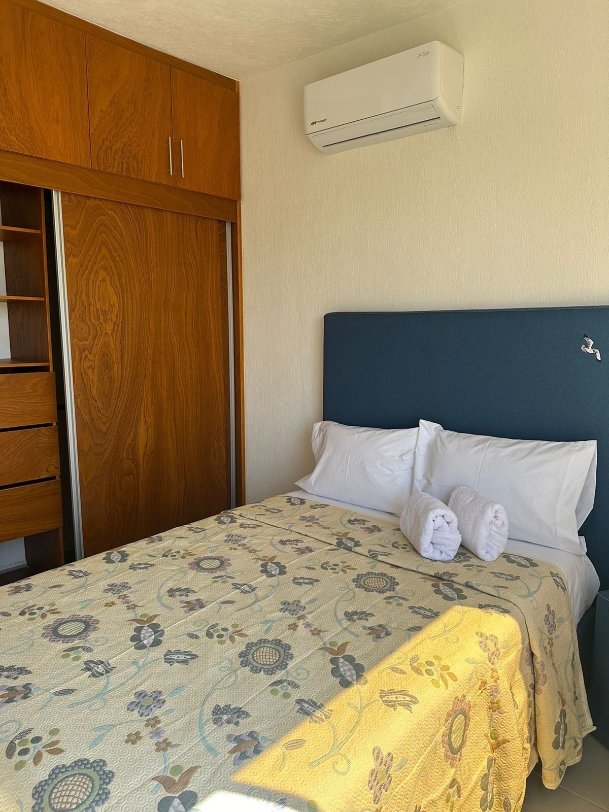 A bedroom with a bed, a wardrobe, and an air conditioning unit.