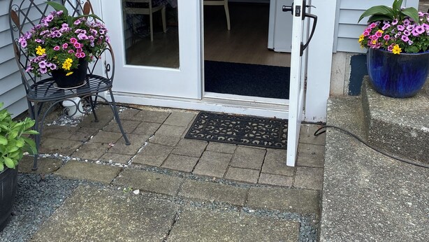 Een glazen schuifdeur die leidt naar een terras met een stoel en plantenpotten.
