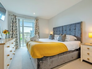 Een moderne slaapkamer met een groot bed, een nachtkastje, een dressoir en uitzicht op de omgeving.