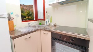 A modern kitchen with a built-in oven, a sink, and a window with a view of a hillside. - Seafront Apartments Anthony (Lastovo)