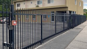 A two-story building with a beige exterior, a black metal fence, and a parking lot. - Cozy Nob Hill Condo close to UNM (Albuquerque)