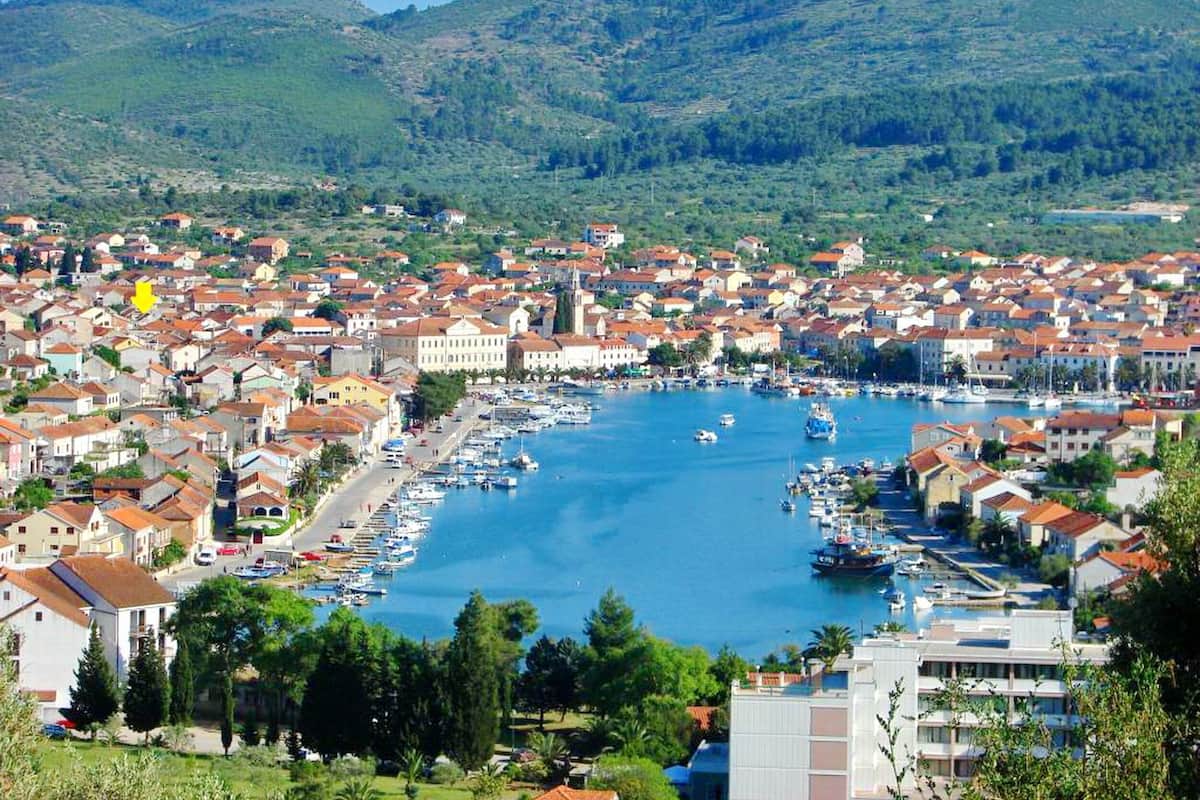 A coastal town with a marina, surrounded by hills and residential buildings.