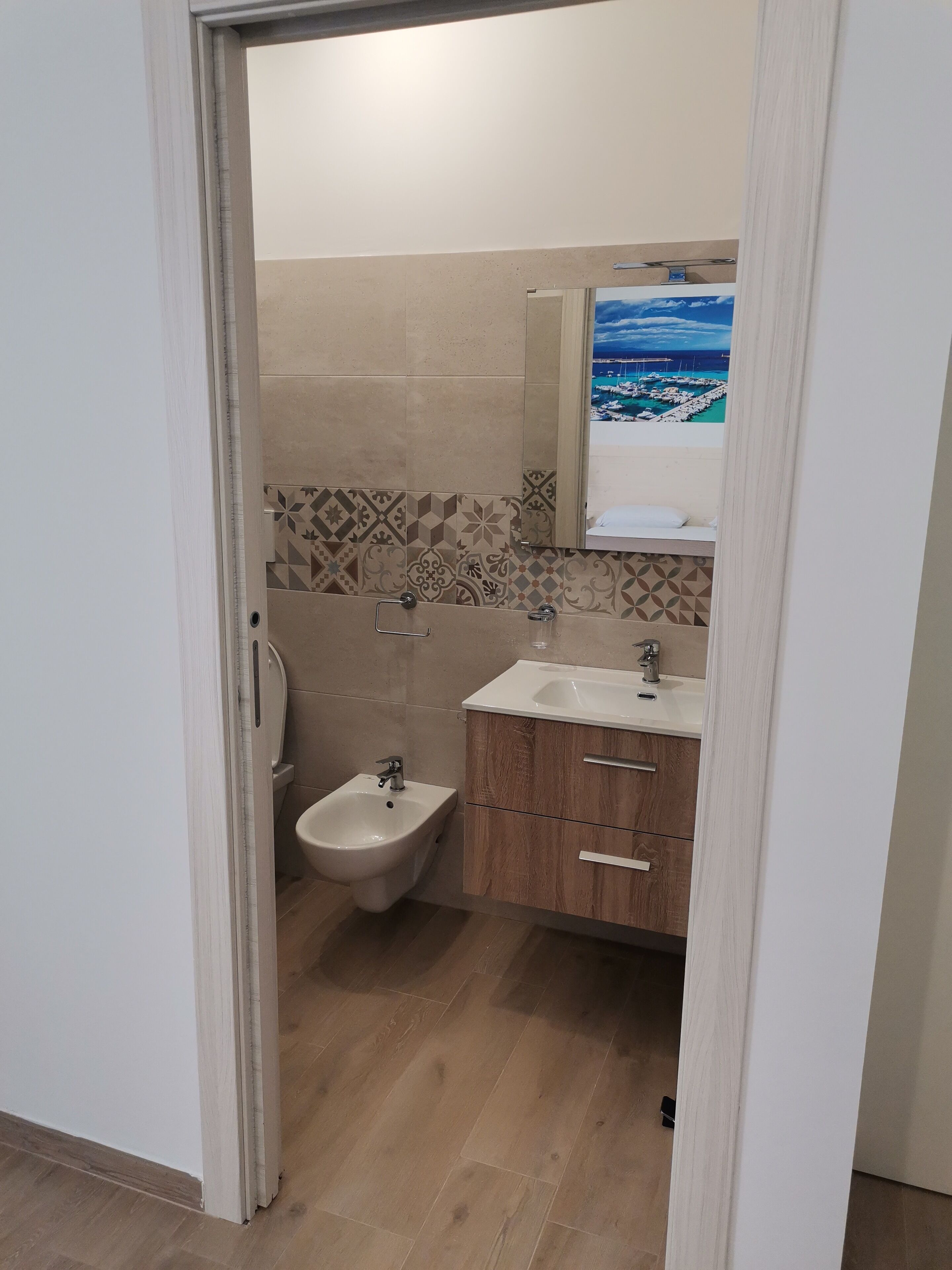 A bathroom with a bidet, a sink, and a mirror reflecting a scenic view.