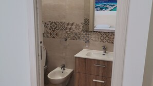 A bathroom with a bidet, a sink, and a mirror reflecting a scenic view. - Paluna (Otranto)