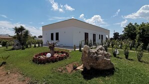 A modern building with a flat roof, surrounded by a well-maintained lawn and a few trees. - Paluna (Otranto)