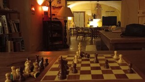 A living room with a chessboard, a television, and a dining area with chairs and a table. - Les Gîtes du mas Champion (Saint-Just-et-Vacquières)