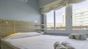 Une chambre d’hôtel avec un lit, une fenêtre avec des rideaux et une vue sur un immeuble.