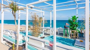 Un espace extérieur abrité, doté de mobilier blanc, d’une piscine et offrant une vue sur la mer.