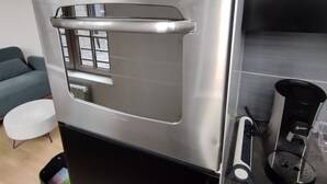 Horno de acero inoxidable con un reloj digital que marca las 8:58, un panel de control con botones y un tirador.
