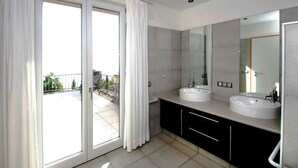 A modern bathroom with two sinks, a large mirror, and a sliding glass door leading to a balcony. - Villa Buena Vista mit Beheiztem Pool und Sauna (Tijarafe)