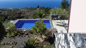 A pool with a view of the ocean, surrounded by greenery and a stone wall. - Villa Buena Vista mit Beheiztem Pool und Sauna (Tijarafe)