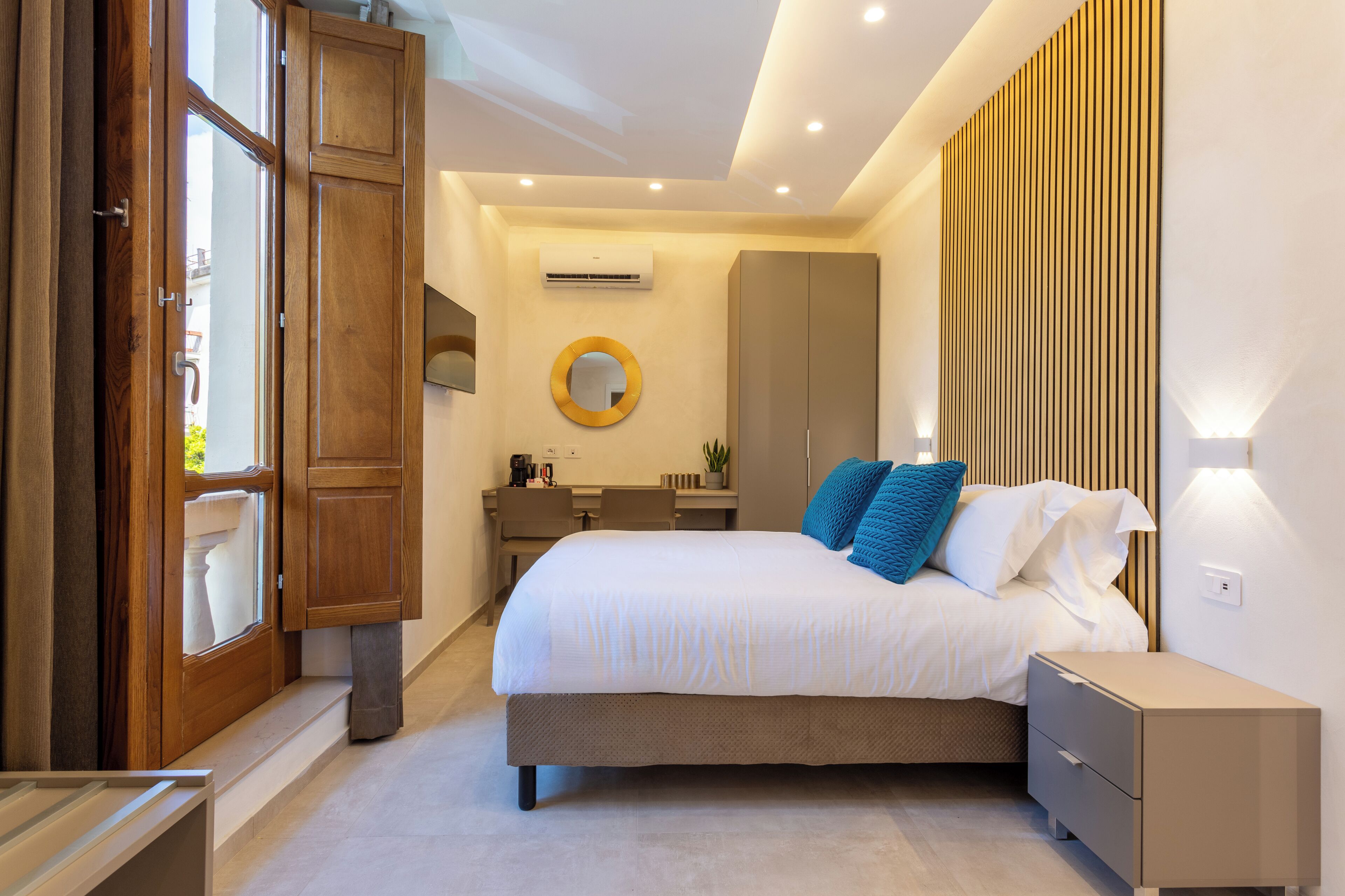 Een moderne slaapkamer met een groot bed, nachtkastjes, een bureau en een kledingkast.