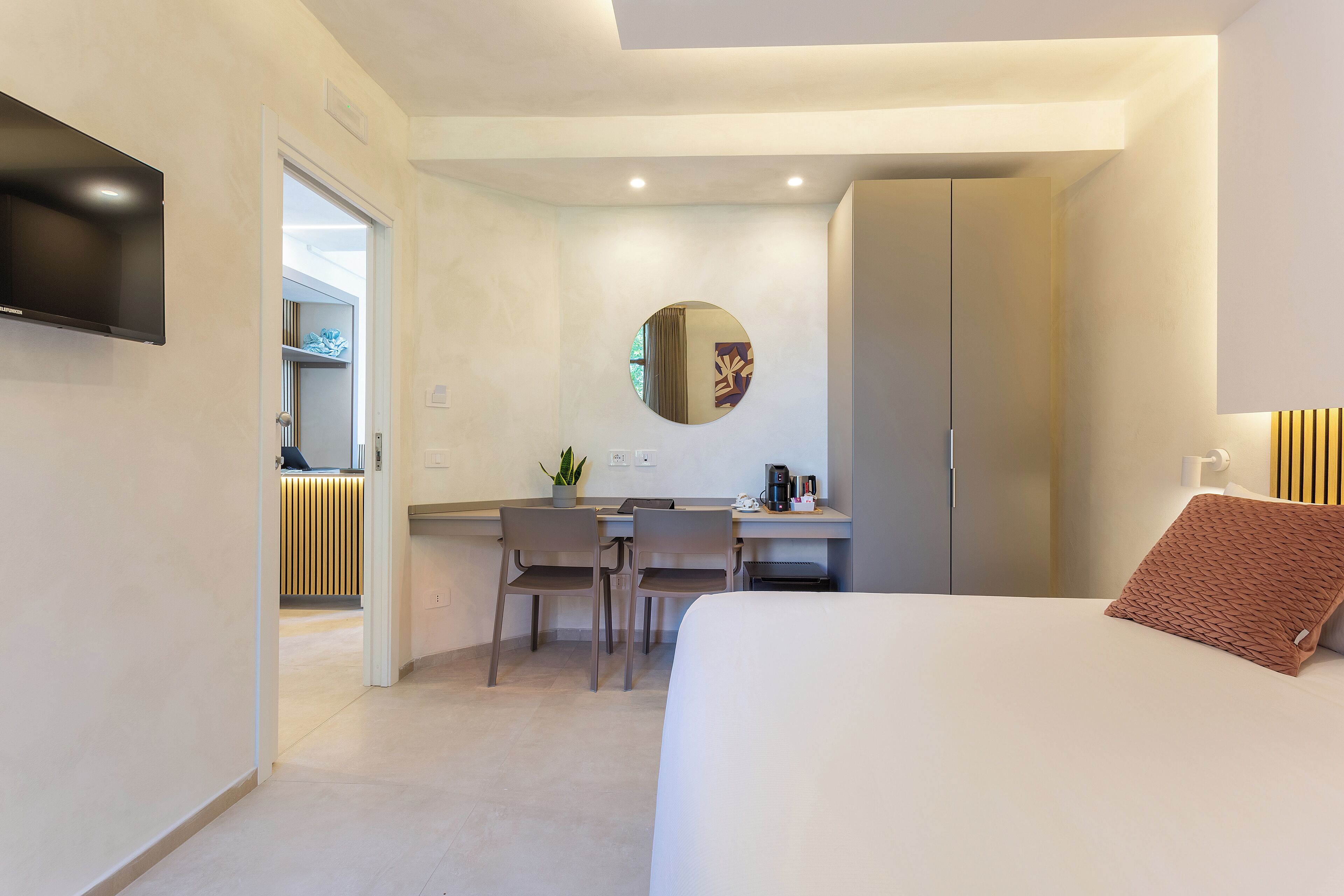 Ein modernes Hotelzimmer mit Bett, Schreibtisch und Fernseher.